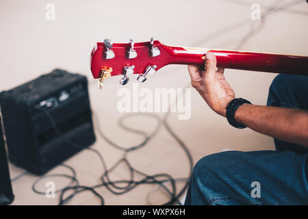 Vista posteriore della mano d'uomo suonando una chitarra elettrica. Messa a fuoco selettiva. Copia dello spazio. Foto Stock