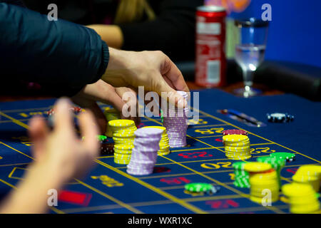 Tavolo da Roulette con mani di uomo mettere giù chip nel casinò. La ruota della roulette in primo piano. Gioco Scommessa. Irriconoscibile la gente. Foto Stock