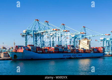 Un vicino l immagine di un contenitore grande nave venga caricato mediante gru con cielo blu sullo sfondo ormeggiata nel porto di Algeciras, Spagna Foto Stock