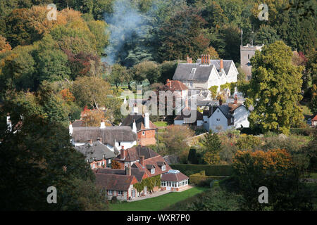 Villaggio di Selborne, Hampshire, Regno Unito, tra cui la chiesa di Santa Maria, visto dal faggio "appendiabiti" sopra il villaggio: Colore di autunno e il falò fumo Foto Stock