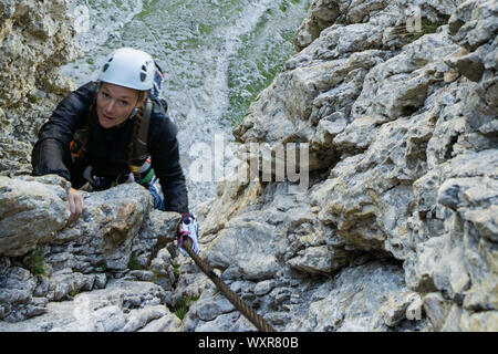 Attraente femmina scalatore di montagna nelle Dolomiti dell'Italia sulla ripida e Poessnecker difficile via ferrata Foto Stock