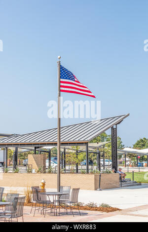 HICKORY, NC, Stati Uniti d'America-13 Settembre 2019: bandiera americana in piedi in una pubblica piazza, con due persone sedute sui gradini. Copia dello spazio. Foto Stock
