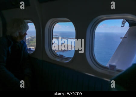 Una donna che guarda fuori dalla finestra di aereo come si decolla da San Marys, aeroporto St Marys isola, isole Scilly, Cornwall, Regno Unito Foto Stock