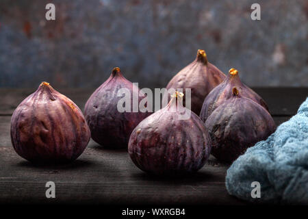 Fichi freschi giacciono su un tavoli in legno nero. Bella blu fig frutti close up Foto Stock
