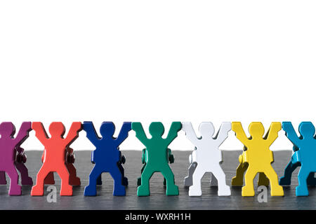 Colorate diverse persone in miniatura statuette in piedi in fila su una pietra scura piastra di ardesia. Isolato su sfondo bianco. La diversità concetto astratto. Foto Stock