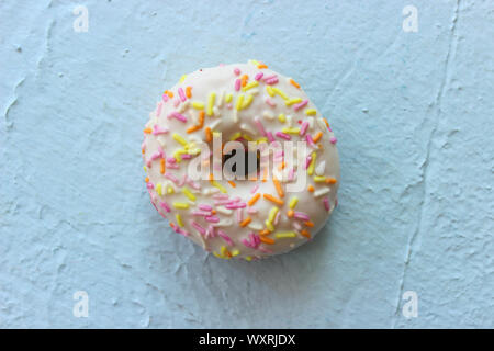 Ciambella in smalto bianco con multi-Spruzzi di colore blu su sfondo a trama close-up Foto Stock