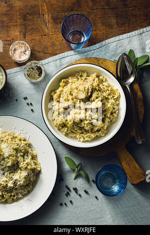 Italiano classico risotto con funghi su un tavolo di legno con un blu tovaglie di lino. vino rosso bottiglia e bicchieri. top scatti Foto Stock