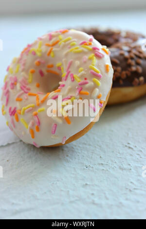 Ciambella in smalto bianco con multi-Spruzzi di colore blu su sfondo a trama close-up Foto Stock