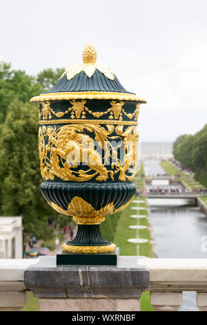 Al Parco di Peterhof, San Pietroburgo, Russia, agosto 2019. Un grande vaso decorato nella parte anteriore del canale principale del parco circondato il grande palazzo Foto Stock