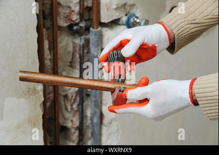 Il lavoratore è usando un tubo di rame taglierina per il taglio di tubi della dimensione desiderata. Foto Stock