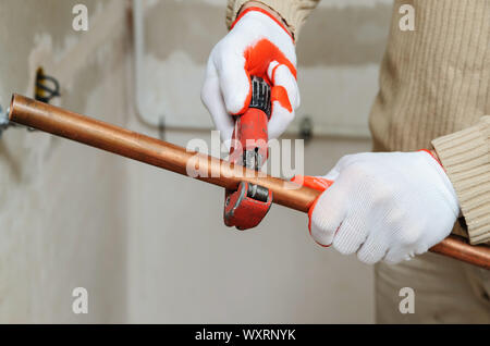 Il lavoratore è usando un tubo di rame taglierina per il taglio di tubi della dimensione desiderata. Foto Stock