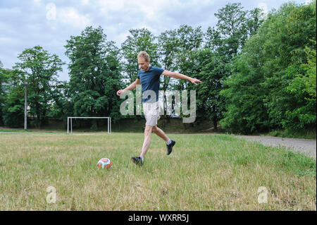 Gioco di calcio. L'uomo è in esecuzione per colpire la palla. Foto Stock