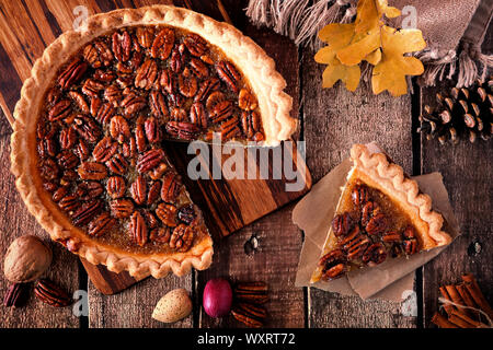 Autunno torta alle noci pecan, overhead tabella in scena con la fetta tagliata su di un legno rustico sfondo Foto Stock