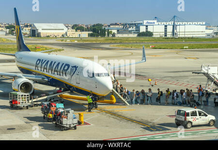 Napoli, Italia - Agosto 2019: i passeggeri di salire a bordo della Ryanair Boeing 737 jet all'aeroporto di Napoli. Il bagaglio viene caricato da carrelli per bagagli Foto Stock