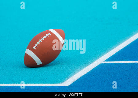La sfera per il football americano su blu corte, all'aperto. American Football palla su un blu sport multifunzionale tribunale aperto Foto Stock