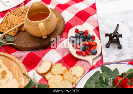 Elegante pic nic sul prato verde. Cornetti freschi e una teiera con il tè su un copriletto vicino a una femmina di vimini hat. Instagram contenuto. Foto Stock