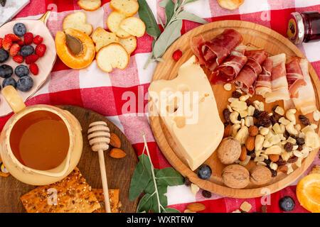 Elegante pic nic sul prato verde. Cornetti freschi e una teiera con il tè su un copriletto vicino a una femmina di vimini hat. Instagram contenuto. Foto Stock