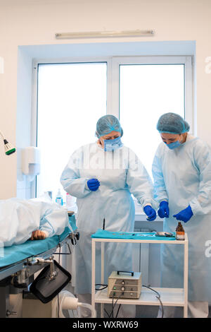 Il chirurgo prende lo strumento dalla tabella. La chirurgia per rimuovere moli in una clinica privata. Foto Stock