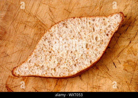 Sezione trasversale di grano bun su ben utilizzati, tagliere di legno. Shot direttamente dall'alto. Foto Stock