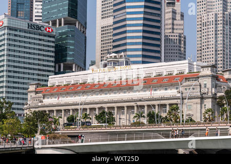 Singapore - Marzo 21, 2019: su Marina acque. Il Fullerton Hotel dietro la strada spianata e Giubileo ponte pedonale. Pareti del distretto finanziario di sky Foto Stock