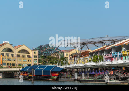 Singapore - Marzo 21, 2019: Closeup di barche sul Fiume Singapore a nord Boat Quay con le sue case colorate, ora bar e ristoranti sotto il cielo blu. Foto Stock