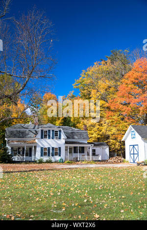 Neat tradizionale in legno tipico Bianchi infissi casa circondata dalla caduta delle foglie, in Conway, New Hampshire, STATI UNITI D'AMERICA Foto Stock