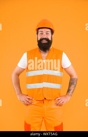 Esperti professionisti. Felice lavoratore professionale su sfondo arancione. La costruzione da parte di un tecnico o di un architetto professionista che indossano uniformi. Essere pronti per attività professionale. Foto Stock