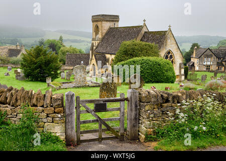 San Barnaba chiesa anglicana con il cimitero e il muro di pietra porta umido in condizioni di tempo piovoso in Snowshill Cotswold Inghilterra Foto Stock