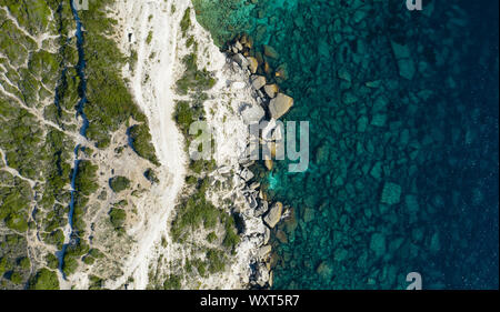 Vista da sopra, splendida vista aerea a una bianca roccia calcarea e formazioni rocciose bagnate da un turchese chiaro acqua, Bonifacio, Corsica, Francia. Foto Stock