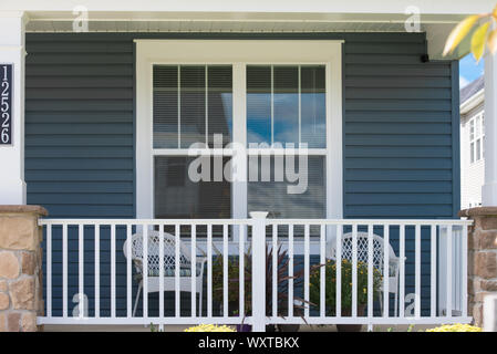 Vista di un portico in una sola famiglia casa di lusso con sedie bianche Picket Fence e doppia pagina appese finestra bianca NEGLI STATI UNITI Foto Stock