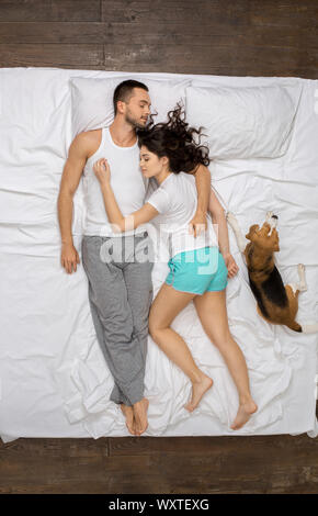 Coppia giovane relax sul letto vista superiore con un cane dorme Foto Stock