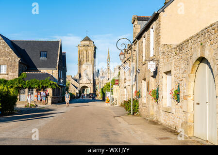 Locronan, Francia - 1 Agosto 2018: vista della strada principale del villaggio medievale di Locronan con la Chiesa sullo sfondo di una giornata di sole di estate Foto Stock