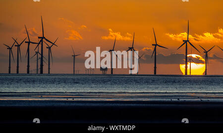 Il sole tramonta dietro Burbo Bank wind farm e 'un altro luogo", un arte di installazione da Anthony Gormley, a Crosby Beach in Merseyside nel nord ovest dell'Inghilterra. Foto Stock