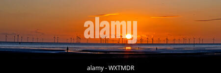 Il sole tramonta dietro Burbo Bank wind farm e 'un altro luogo", un arte di installazione da Anthony Gormley, a Crosby Beach in Merseyside nel nord ovest dell'Inghilterra. Foto Stock