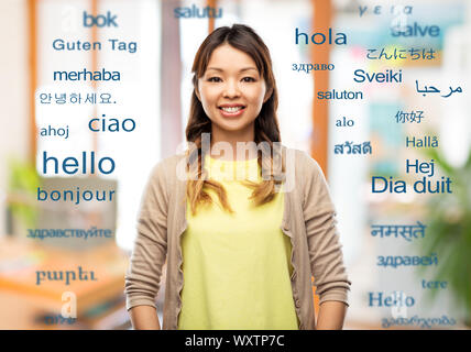 Educazione, comunicazione e il concetto di traduzione - happy asian giovane donna su parole di saluto in diverse lingue straniere Foto Stock