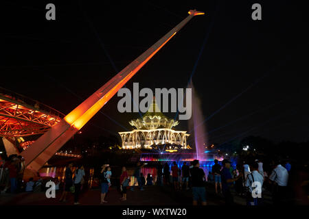 Le persone si radunano di notte per guardare la fontana di acqua e luce laser show di fronte al Sarawak legislativo complessivo stato edificio. In Kuching, Sara Foto Stock