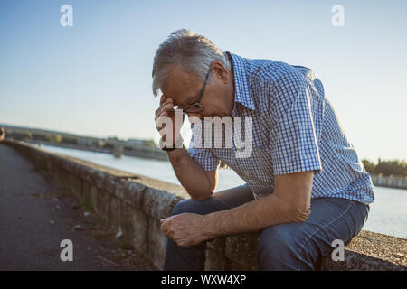 Outdoor ritratto di senior uomo che sta avendo mal di testa. Foto Stock