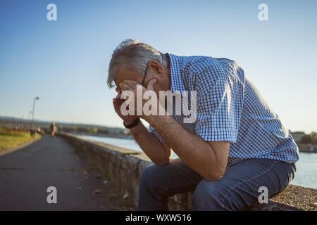 Outdoor ritratto di senior uomo che sta avendo mal di testa. Foto Stock