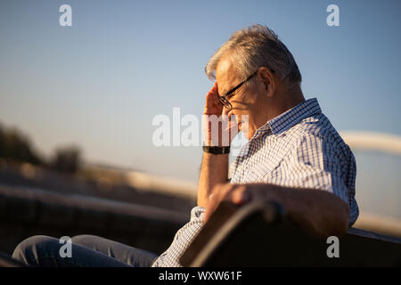 Outdoor ritratto di senior uomo che sta avendo mal di testa. Foto Stock