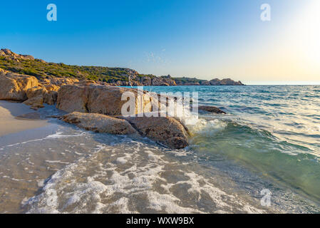 Vista ravvicinata di eroso grigie rocce granitiche sul "Plage d'Argent", prese alla fine del pomeriggio con una barca a vela in background e una piccola w Foto Stock