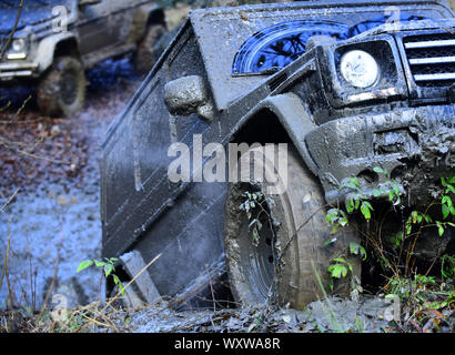 Le ruote sporche di filatura auto nel fango. SUV in autunno la foresta, sfocato. Offroad gara sul giorno di caduta. Intrattenimento estremo concetto. Sporco offroad overc SUV Foto Stock