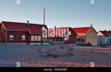 Uomo sulla moto quad passando moderno tipico case svedesi al crepuscolo, Sandhamn, arcipelago di Stoccolma, Svezia Foto Stock