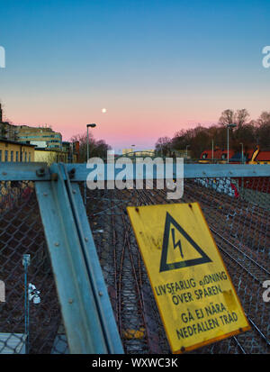 Luna piena all'alba sopra le linee ferroviarie, Stoccolma, Svezia Foto Stock