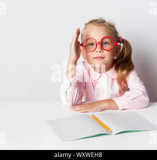 Una scolaretta con gli occhiali in una tabella Foto Stock