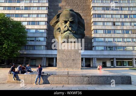 CHEMNITZ, Germania - 8 Maggio 2018: persone sedersi dal grande monumento a Karl Marx a Chemnitz, Germania. Il monumento è noto localmente come Nischel. È stato design Foto Stock