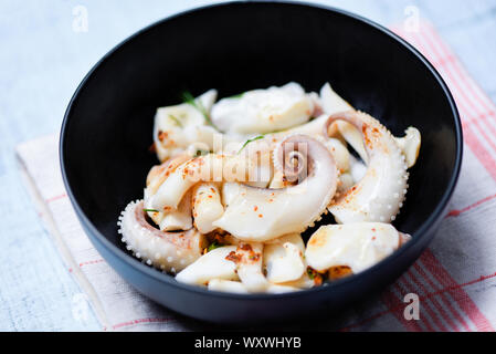 Insalata di calamari ciotola con erbe e salsa di spezie piatti di pesce sul tavolo da pranzo / tentacoli di polpo antipasto cotto cibo cotto nel ristorante Foto Stock