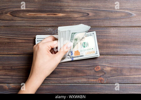 Vista dall'alto di mani femminili conteggiare denaro. Un centinaio di dollari di banconote su sfondo colorato. Il concetto di business. Foto Stock
