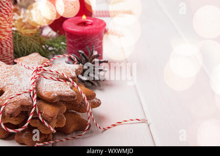 Pila di fiocchi di neve biscotti di forma in polvere con la glassa di zucchero vicino sul tavolo con decorazioni di Natale e bokeh effetto luci Foto Stock