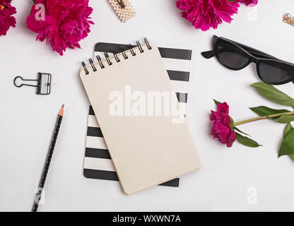 Blocco note mock-up. Creative piatto estivo lay con peonie e accessori femminili, vista dall'alto Foto Stock