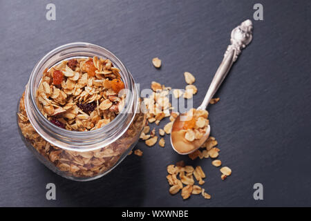 Il Granola Homemede con noci e semi in un vaso di vetro sulla tavola nera Foto Stock